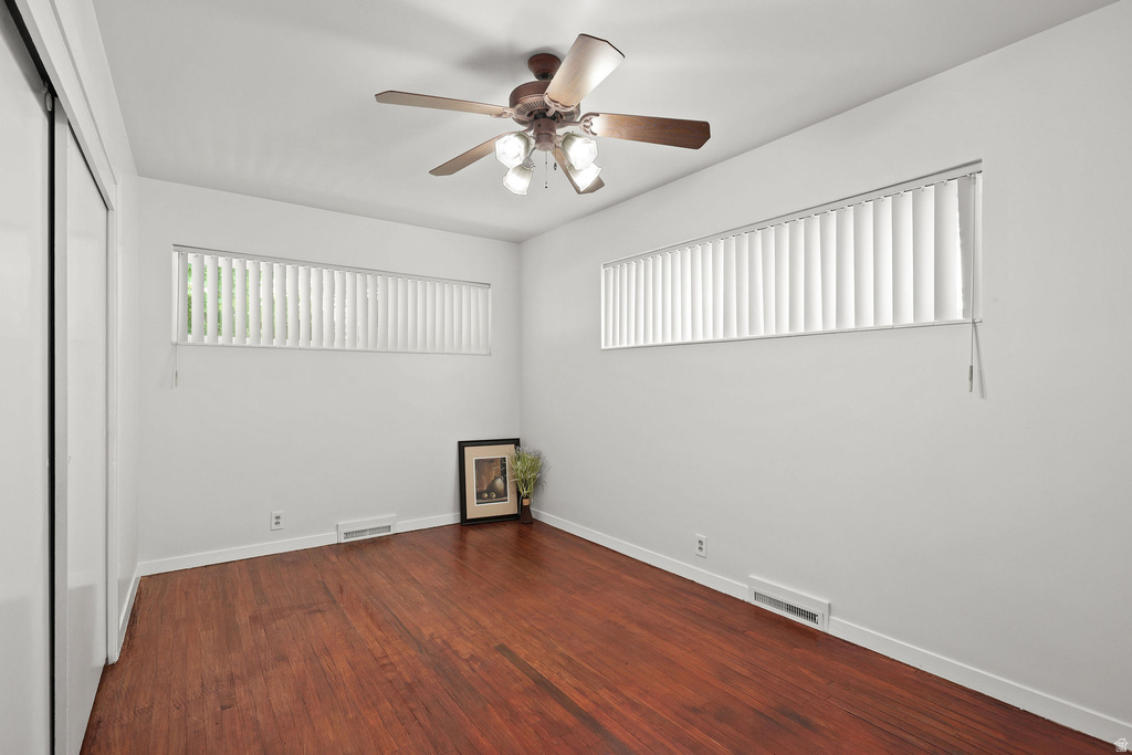 Room featuring wood-finish flooring, white walls, and a ceiling fan with light fixture