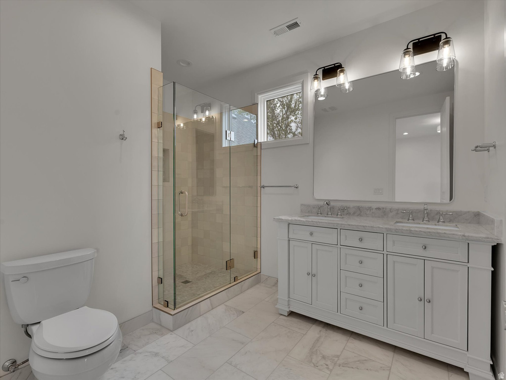 Full bathroom featuring double vanity, a stall shower, and light marble finish floors