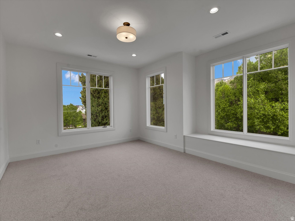 Empty room featuring light carpet, recessed lighting, and plenty of natural light