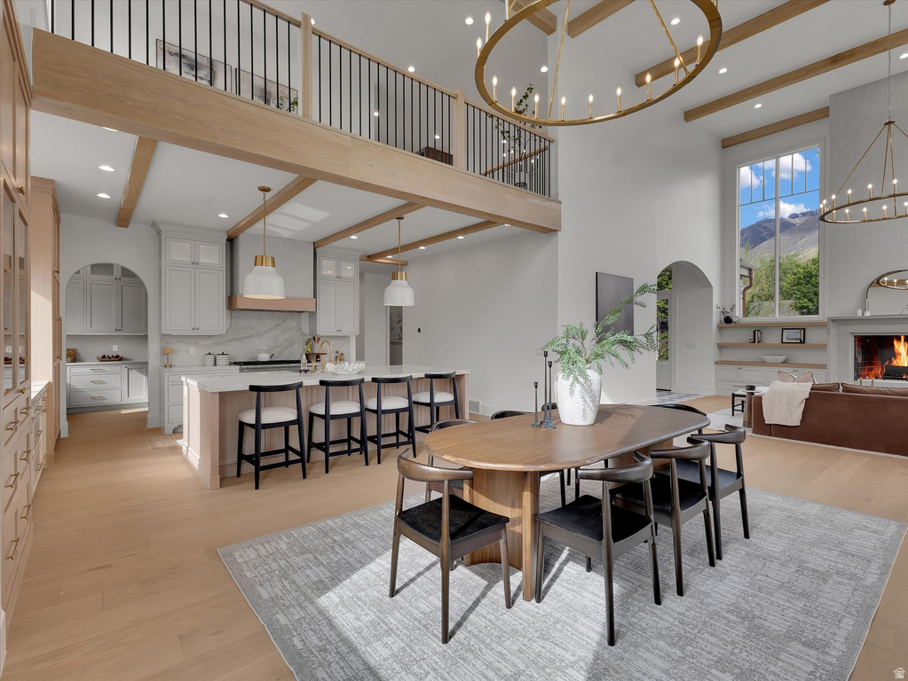 Dining area featuring light wood-style flooring, arched walkways, a chandelier, a mountain view, and a high ceiling