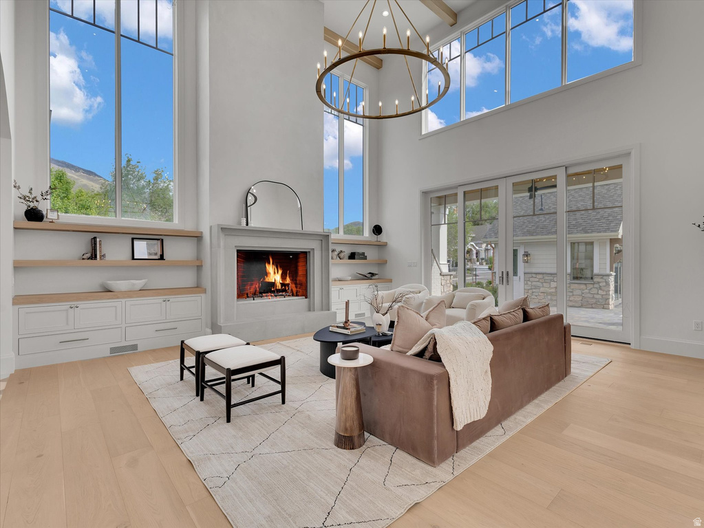 Living room featuring light wood finished floors, a warm lit fireplace, and suspended lighting
