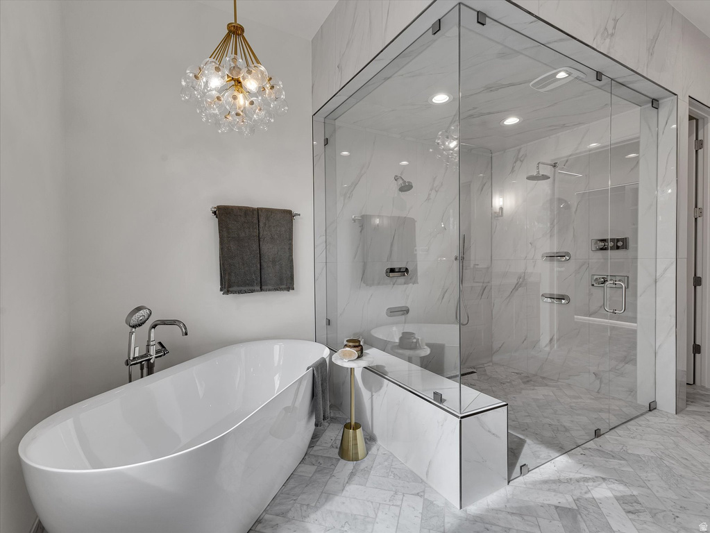 Full bath with a freestanding tub, light marble finish floors, hanging lights, and a marble finish shower