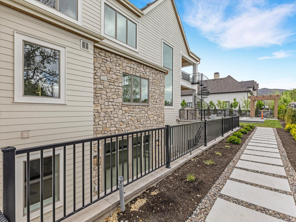 View of side of home featuring stone siding, a balcony, and a patio area