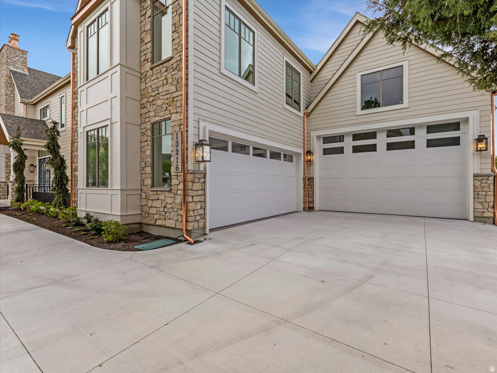 Traditional-style house with stone siding, driveway, and an attached garage