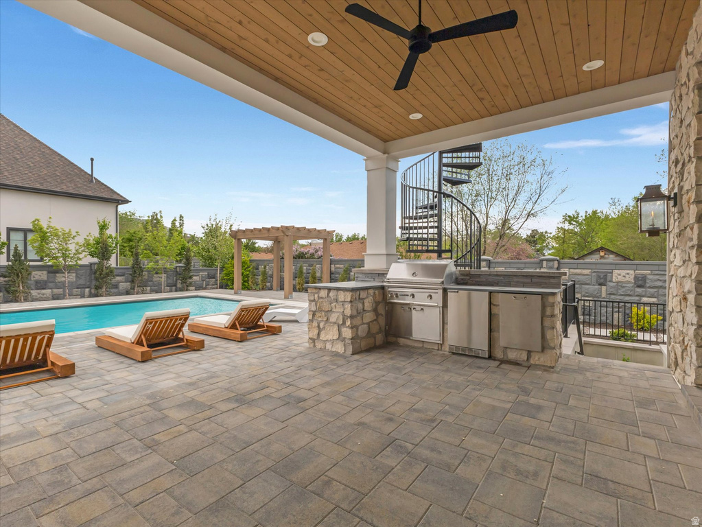 Fenced backyard featuring an outdoor kitchen, a ceiling fan, a patio, and a pergola