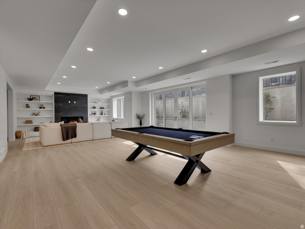 Rec room featuring light wood finished floors, pool table, a fireplace, recessed lighting, and built in shelves