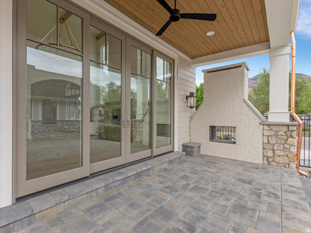 View of patio featuring an outdoor brick fireplace, french doors, and ceiling fan