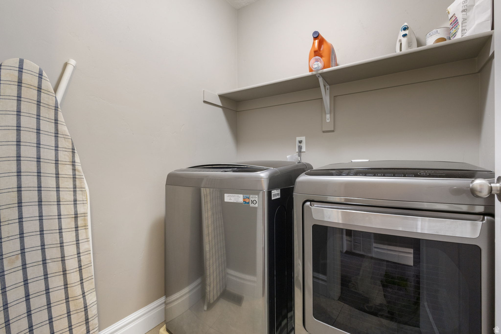 Laundry room with independent washer and dryer and light tile patterned flooring