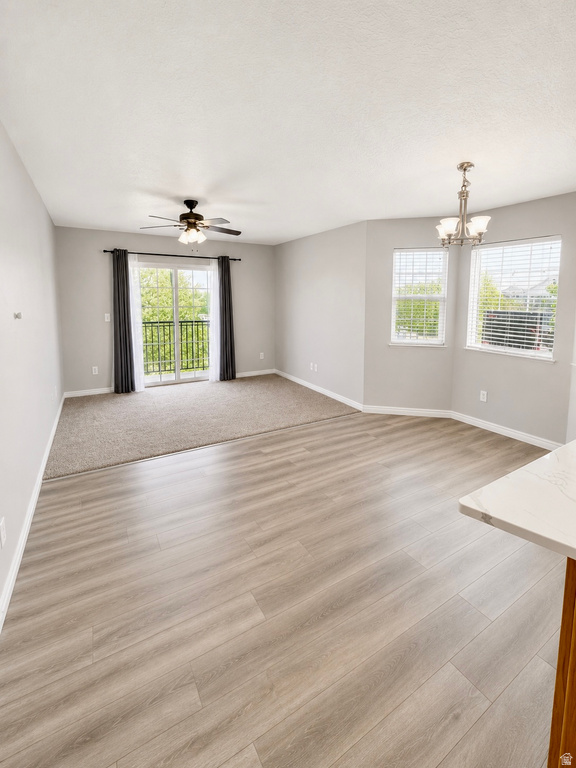 Open-concept living space featuring wood-finish flooring, a ceiling fan, and a chandelier lighting fixture