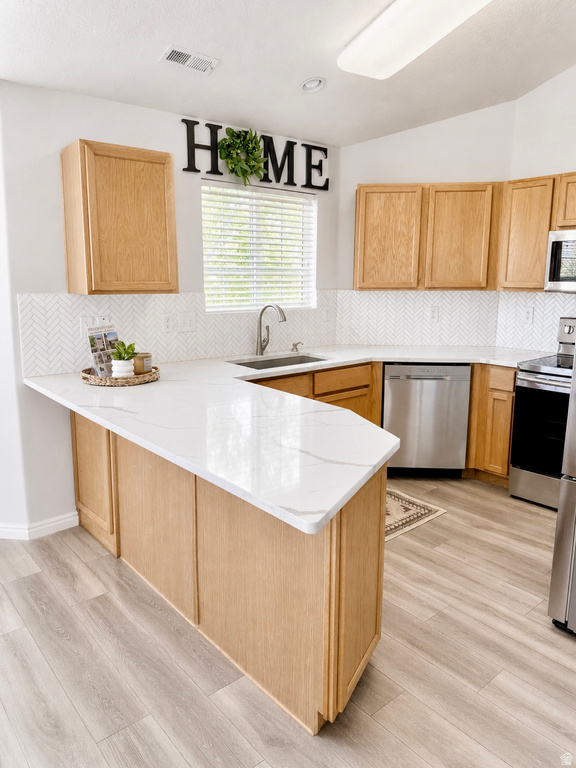Modern kitchen featuring light wood-finish cabinetry, white countertops with subtle gray veining, and a white herringbone tile backsplash