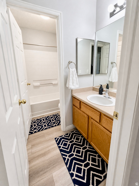 Bathroom featuring a single vanity with wood cabinetry, a built-in sink, and a large wall-mounted mirror