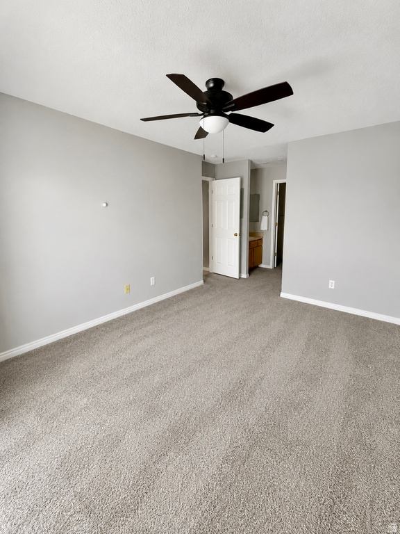 Spacious room featuring light gray walls, textured carpet flooring, and white baseboards