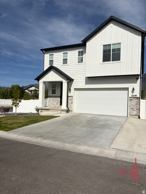 View of front of house featuring board and batten siding, an attached garage, and stone siding
