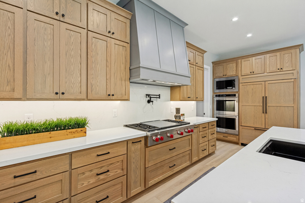 Gourmet kitchen featuring custom wood cabinetry, stainless steel appliances, a range with a griddle, a panel-front refrigerator, and white countertops