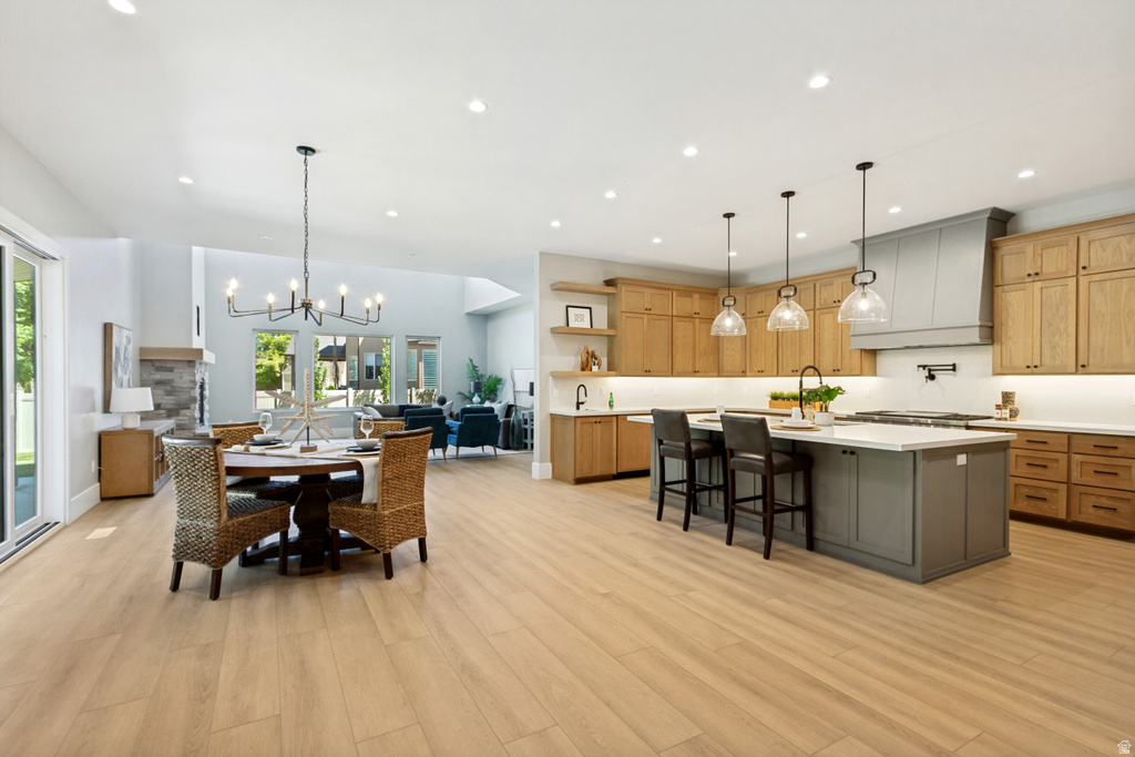 Open-concept space featuring wood-finish flooring, a kitchen island with seating, pendant lighting, and a chandelier in the dining area