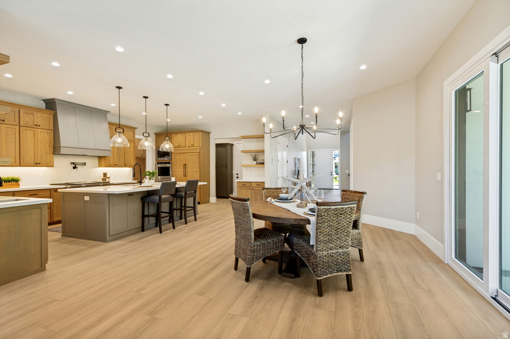 Open-concept living space featuring wood-finish flooring, a kitchen island with seating, pendant lighting, recessed ceiling lights, and a sliding glass door
