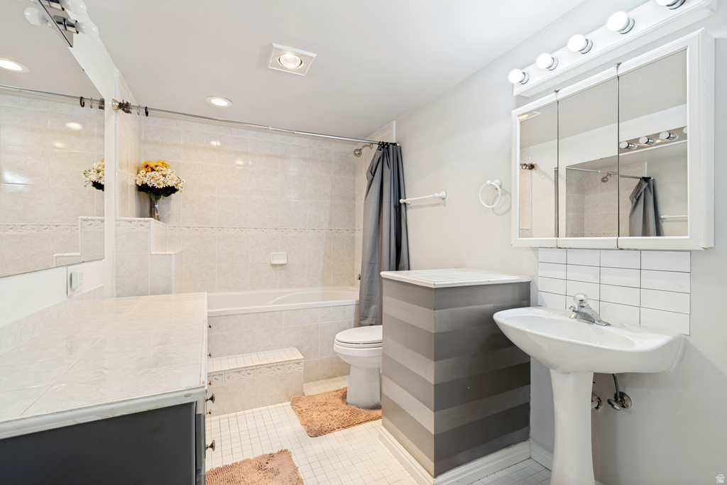 Bathroom featuring a tiled tub surround, recessed lighting, and a pedestal sink