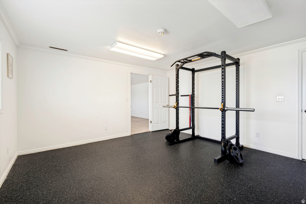 Dedicated fitness room featuring durable rubber flooring, white walls, and bright overhead lighting