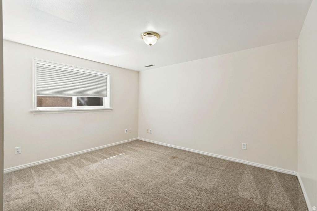 Windowed interior space with light-toned walls and neutral carpeting