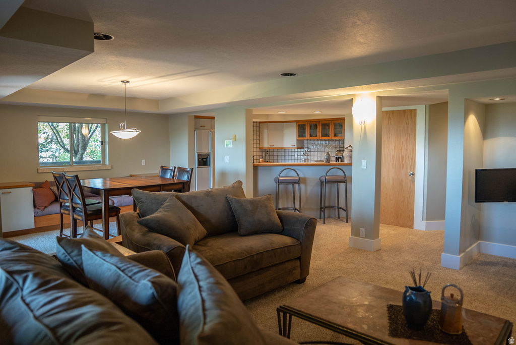 Open-concept living space with recessed lighting, carpeted flooring, and a dining area featuring a window seat with storage