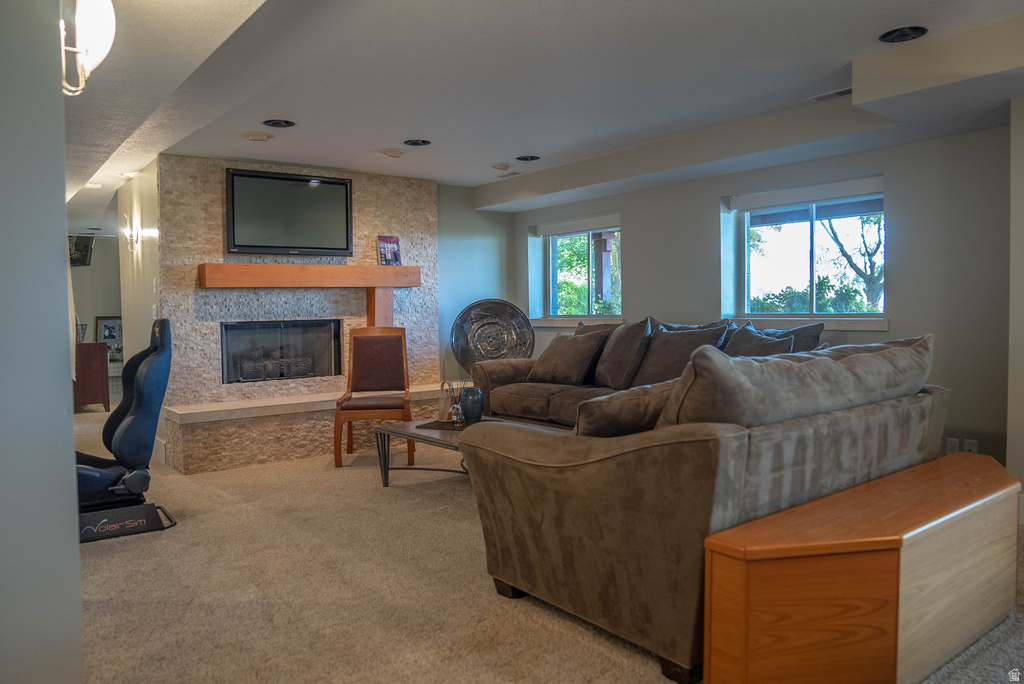 Spacious finished room featuring a stone-faced fireplace with a wood mantle, an integrated television, recessed lighting, and twin windows