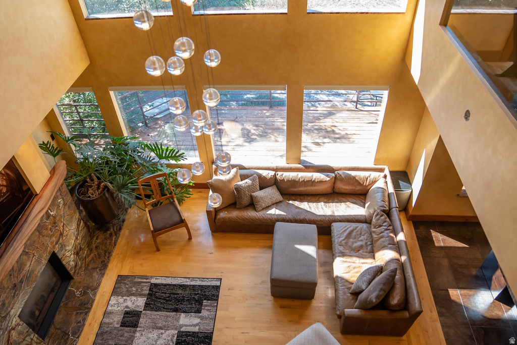 Two-story living area featuring a multi-globe pendant light fixture, wood-finish flooring, and a stone-clad fireplace