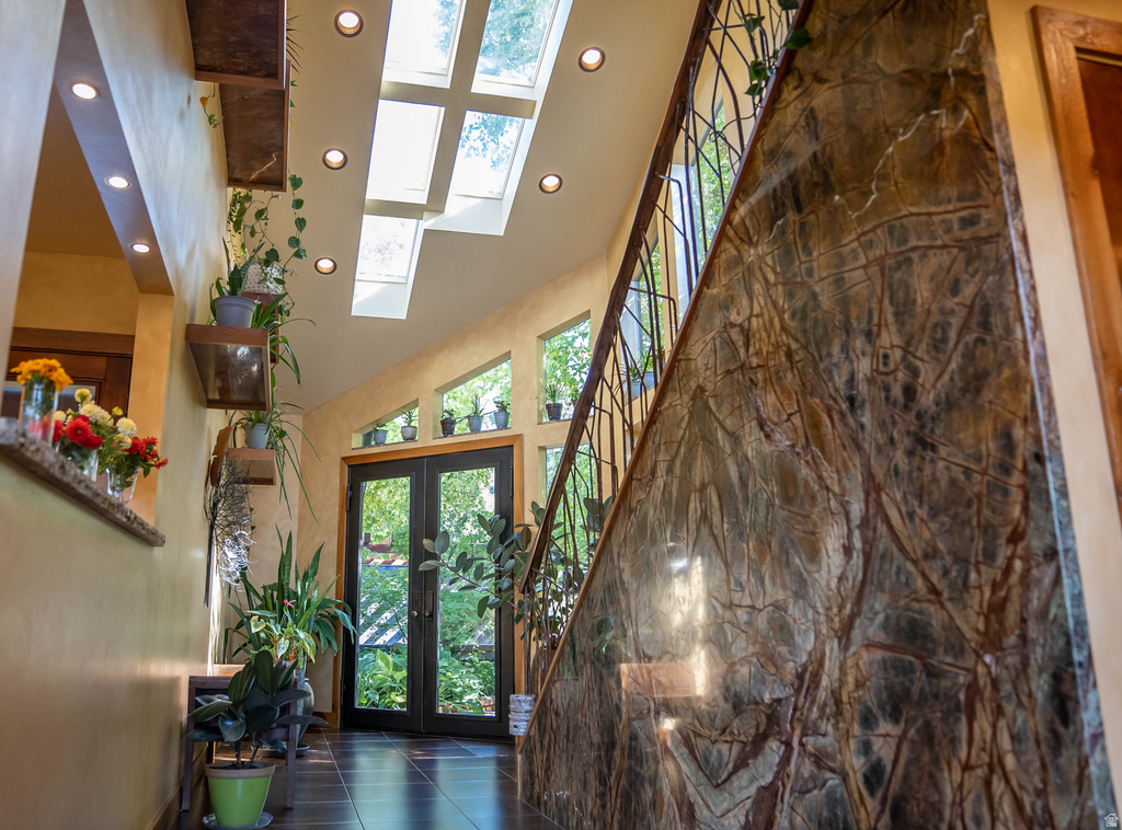 Entryway featuring a natural stone accent wall, dual glass-paneled entry doors, and skylights