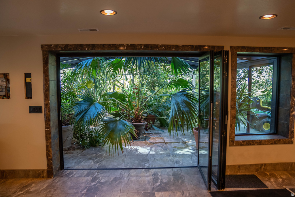 Expansive glass bi-fold doors open to a stone patio with lush tropical landscaping