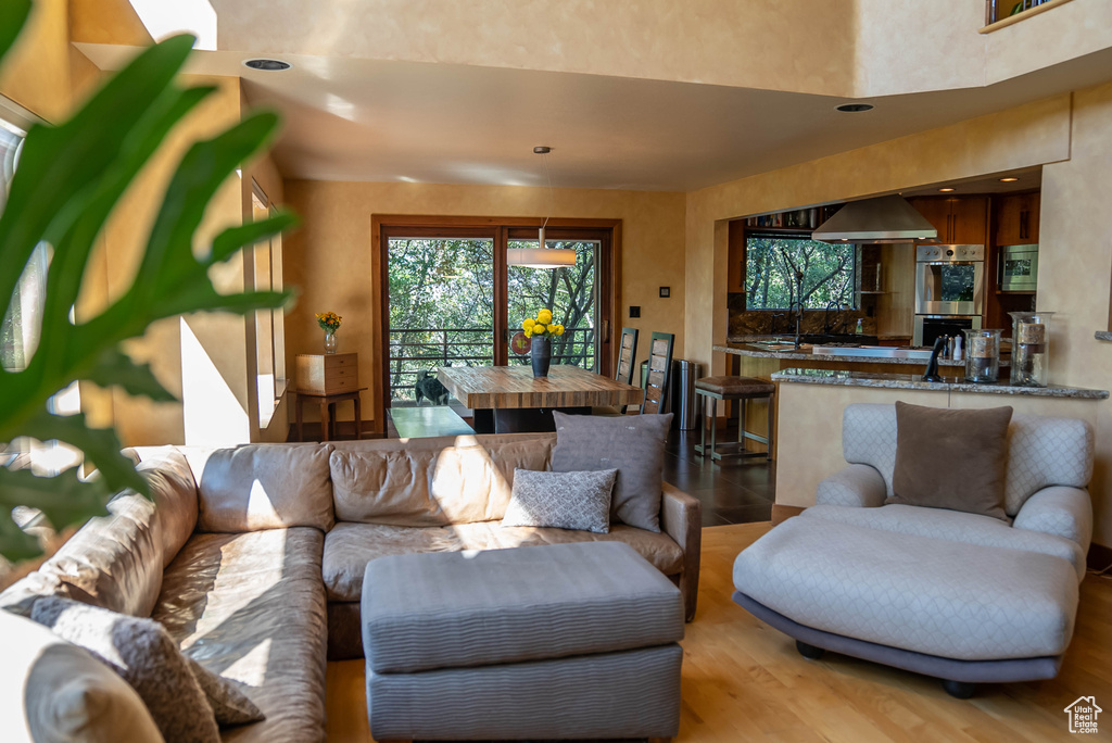Open-concept living space featuring wood-finish flooring, recessed lighting, a dining area with outdoor access, and a kitchen with built-in stainless steel appliances and a breakfast bar