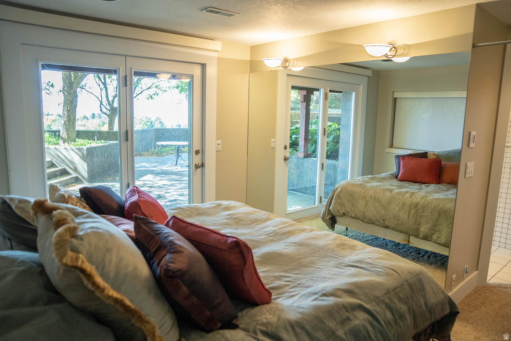 Bedroom featuring direct outdoor access through double glass doors to a stone patio