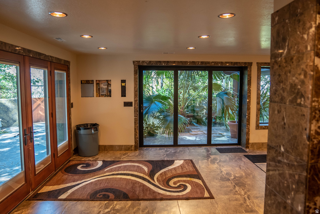 Tiled flooring throughout with recessed lighting, full-light French doors, and a multi-panel glass door offering exterior access