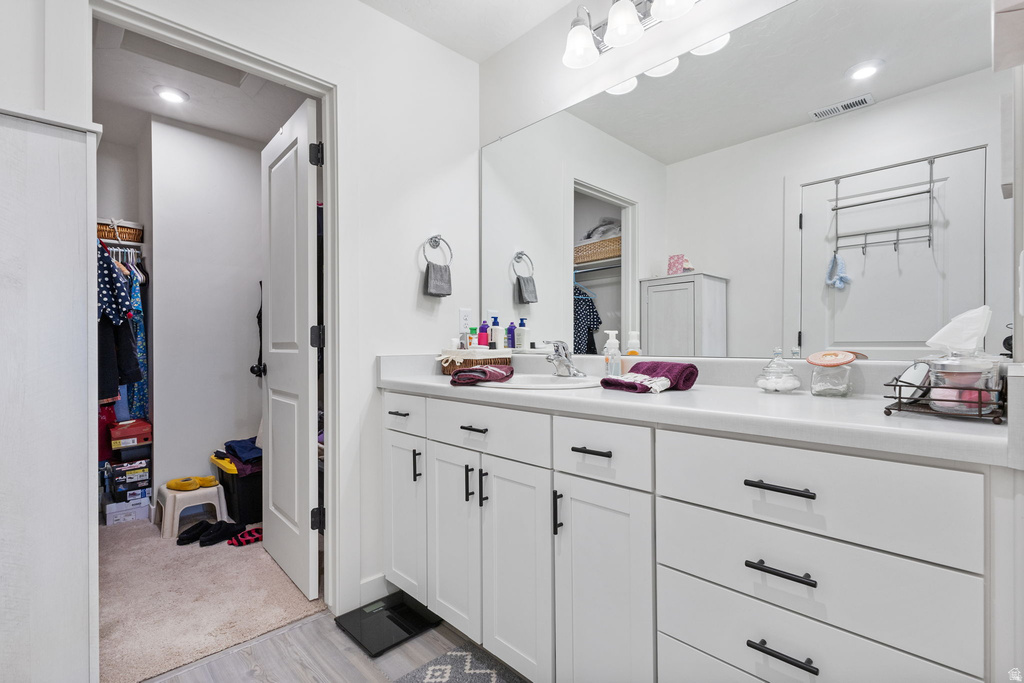 Full bathroom featuring a spacious closet, vanity, recessed lighting, and light carpet