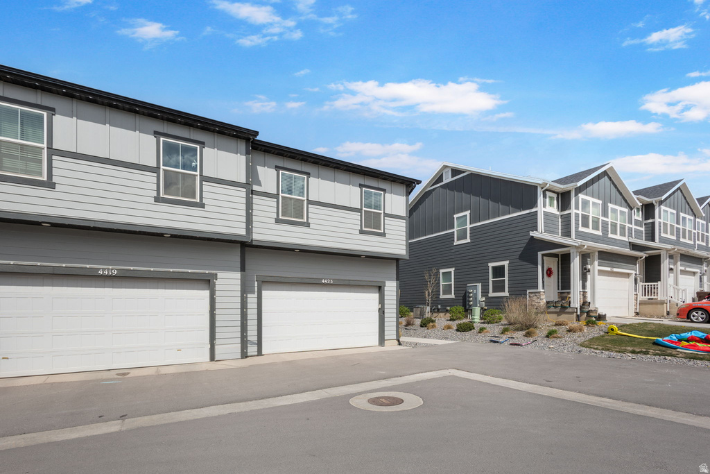 View of front of house with board and batten siding, a garage, and a residential view