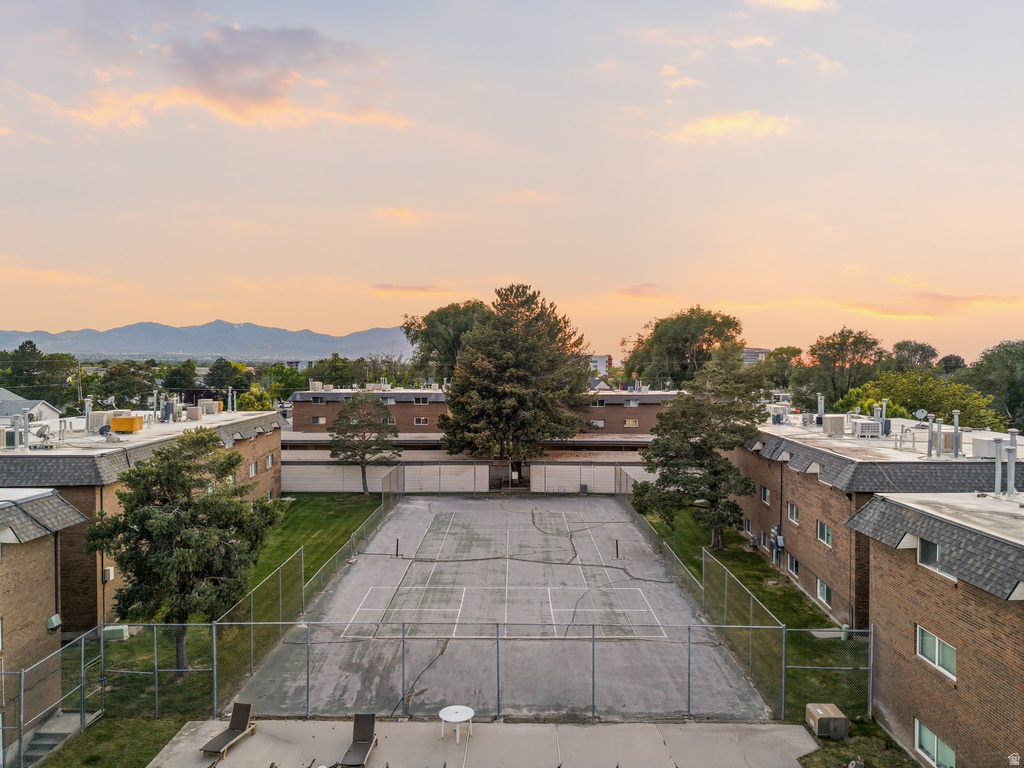 Community tennis court bordered by residential buildings with mountain scenery in the distance