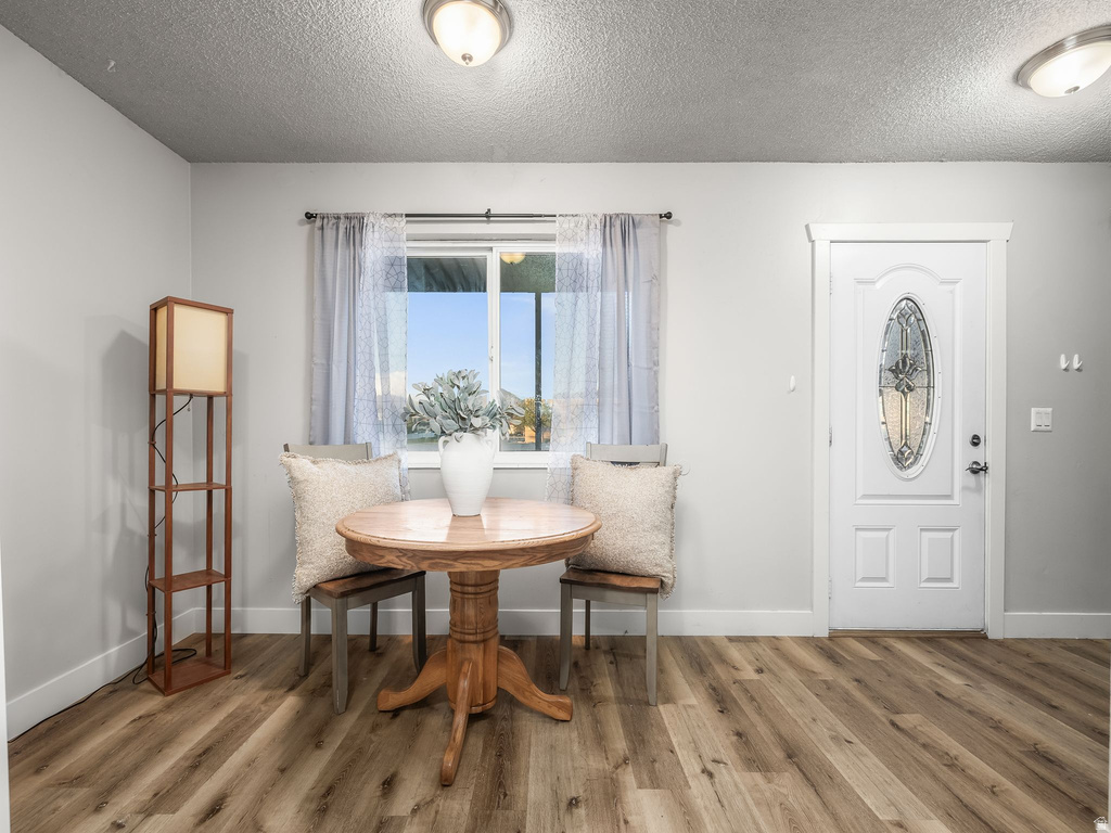 Entryway featuring wood-finish flooring, a white paneled door with an oval decorative glass insert, and neutral wall tones
