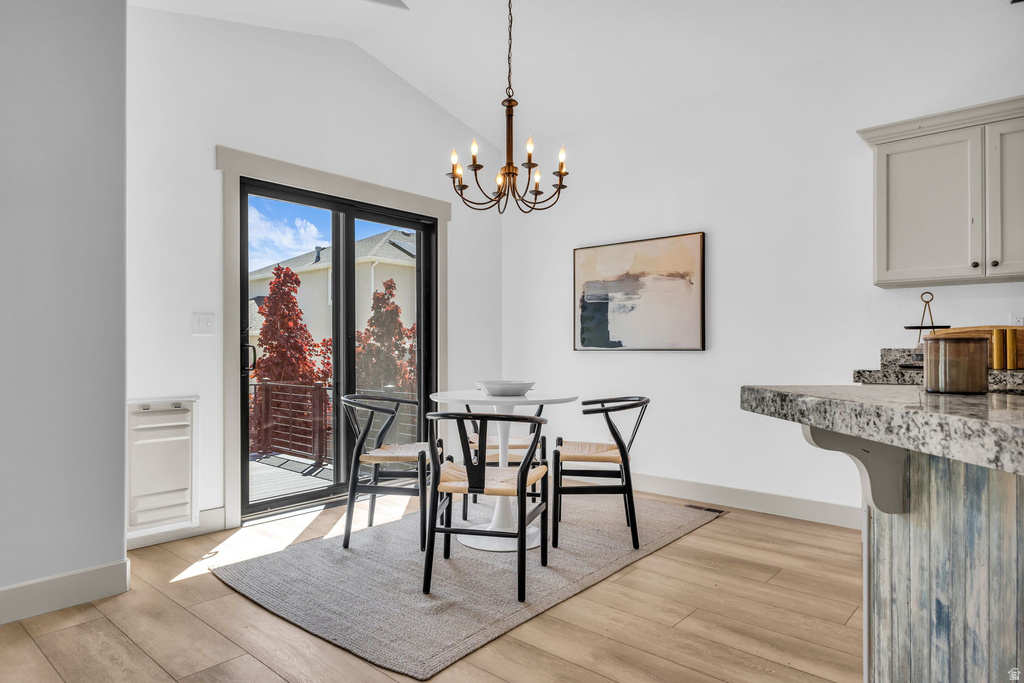 Dining area featuring vaulted ceilings, wood-finish flooring, and a sliding glass door leading to an outdoor deck