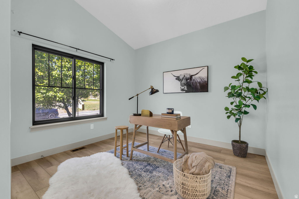 Vaulted ceiling room with wood-finish flooring