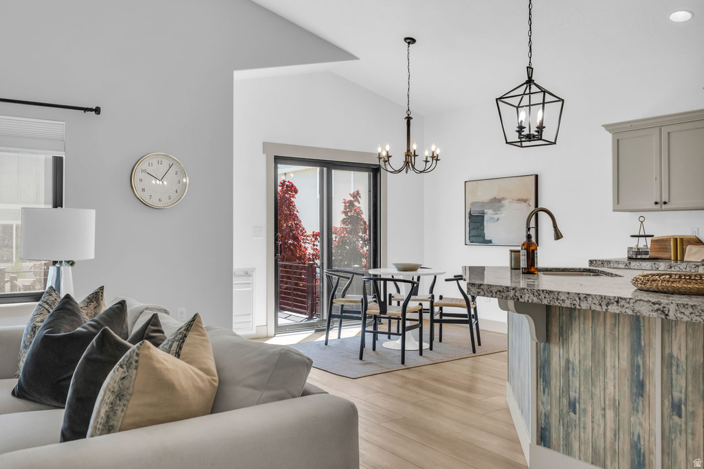 Open-concept living area with light wood-finish flooring, a kitchen island featuring a stone-finish countertop and decorative paneling, and a dining area with direct access to an outdoor space