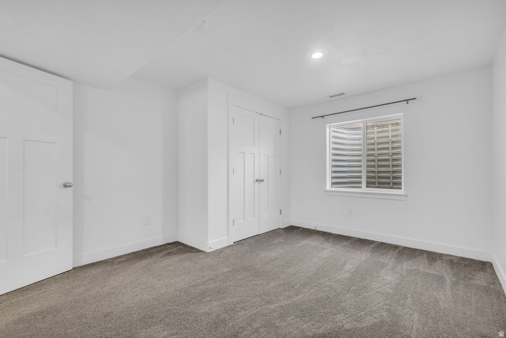 Carpeted room featuring a white window frame, recessed lighting, white baseboards, and two white panel doors