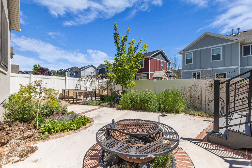 Spacious backyard featuring a built-in fire pit, paved patio, and mature landscaping
