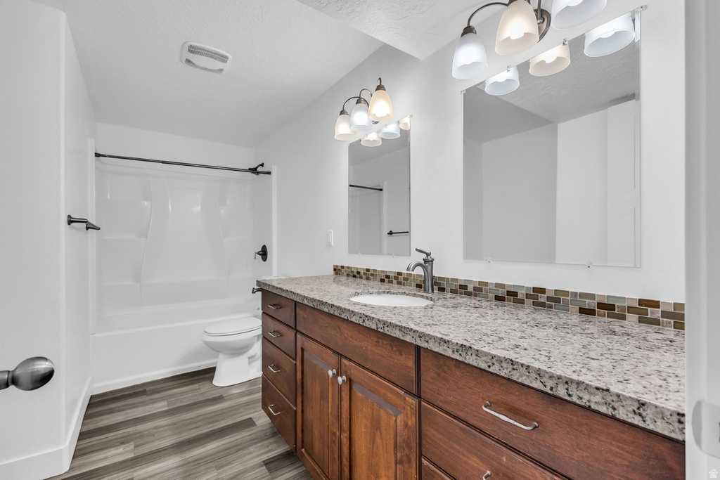 Bathroom featuring a dark wood-finish double vanity with stone-finish countertops, dual mirrors, and a tiled backsplash