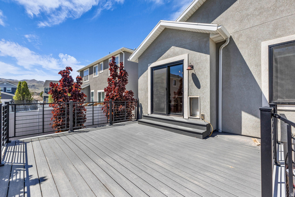Spacious composite deck with black metal railings, leading to a sliding glass door entry
