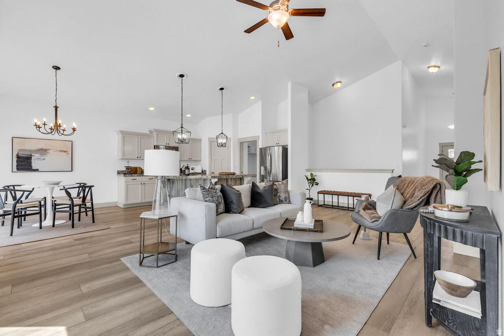 Spacious open-concept living area featuring wood-finish flooring, vaulted ceilings, and recessed lighting