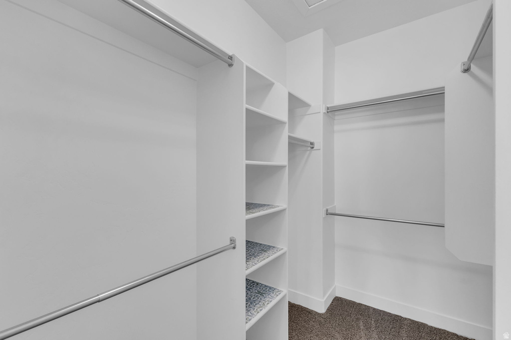 Walk-in closet featuring white built-in shelving, multiple hanging rods, and patterned shelf liners