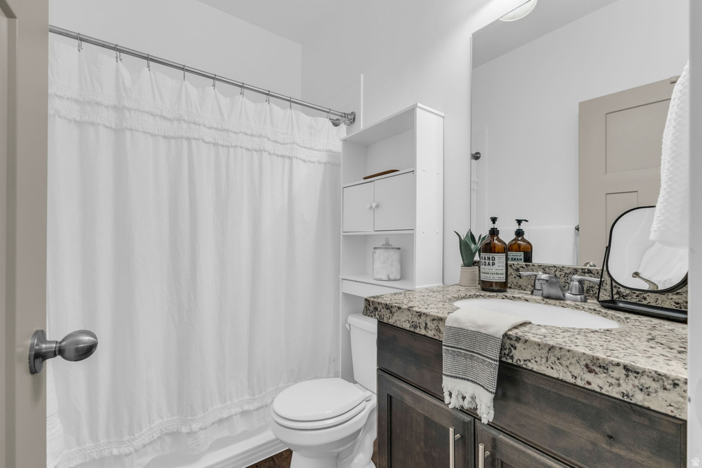 Bathroom featuring a dark wood-finish vanity with a light-toned speckled countertop, an undermount sink, and a large wall-mounted mirror