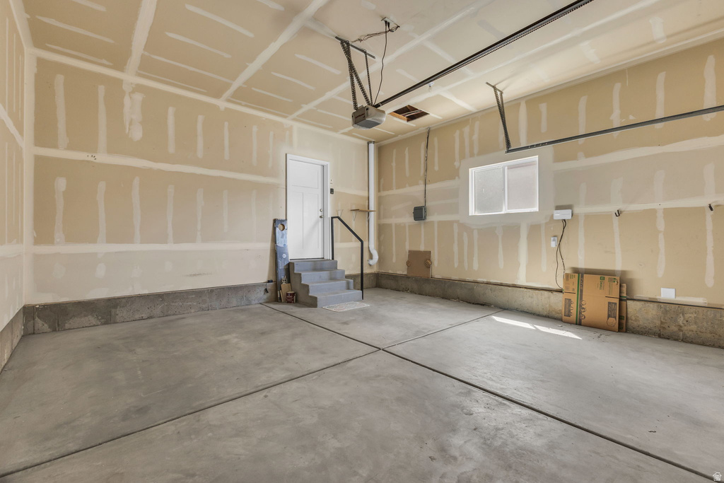 Spacious garage with exposed drywall, concrete flooring, and an overhead garage door opener