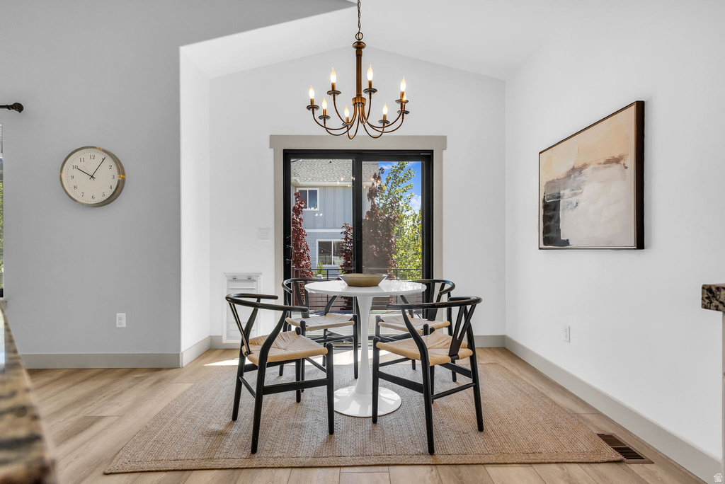Vaulted ceilings elevate this dining area, featuring wood-finish flooring and a bronze chandelier