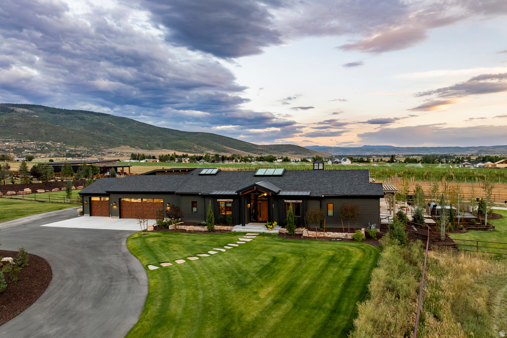 Contemporary ranch-style residence featuring dark siding, a multi-car garage with wood-finish doors, and a skylight-equipped roof