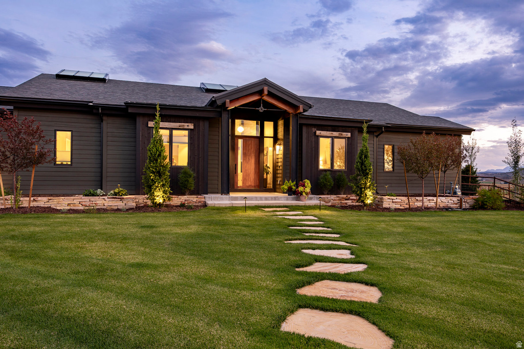 Modern exterior featuring dark siding, stone veneer accents, and a prominent wood-clad entry