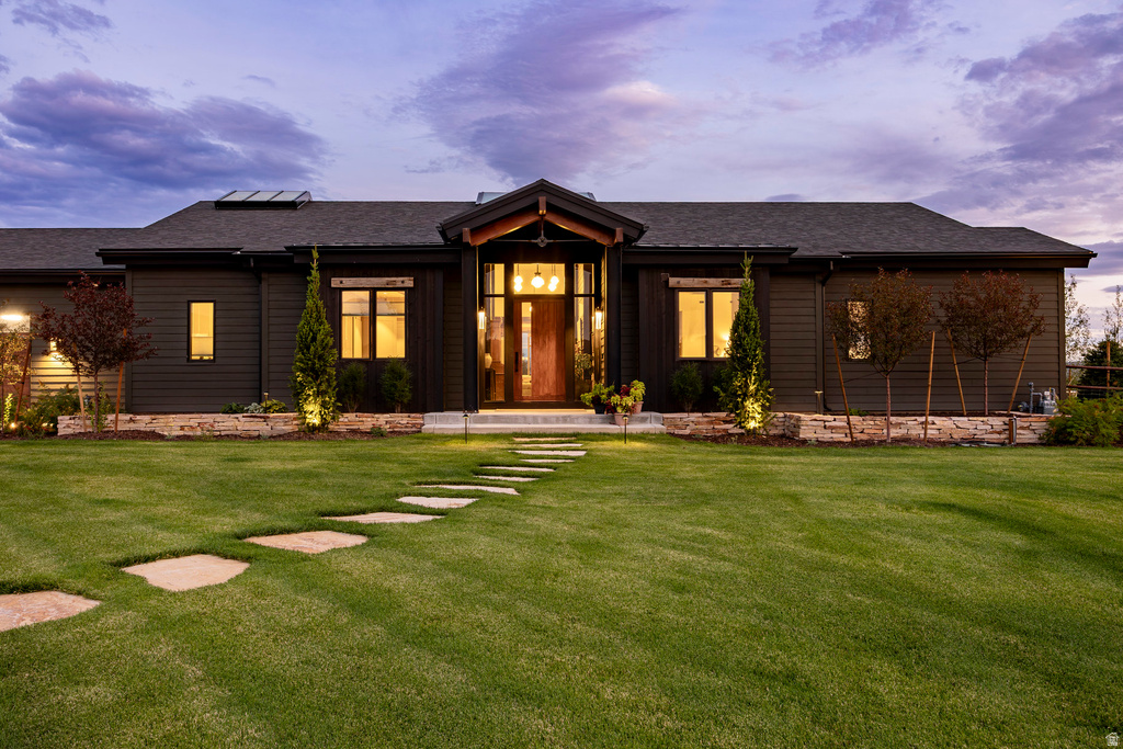 Contemporary ranch-style residence featuring a dark horizontal siding exterior and a prominent gabled entry with a solid wood door